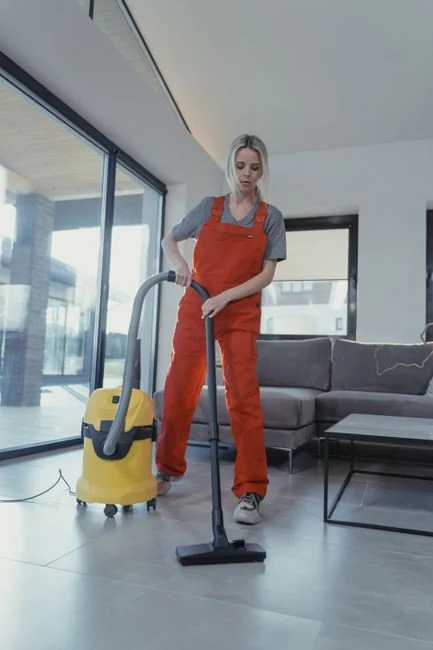 A man in coveralls cleans a large window in a stylish, modern home interior.